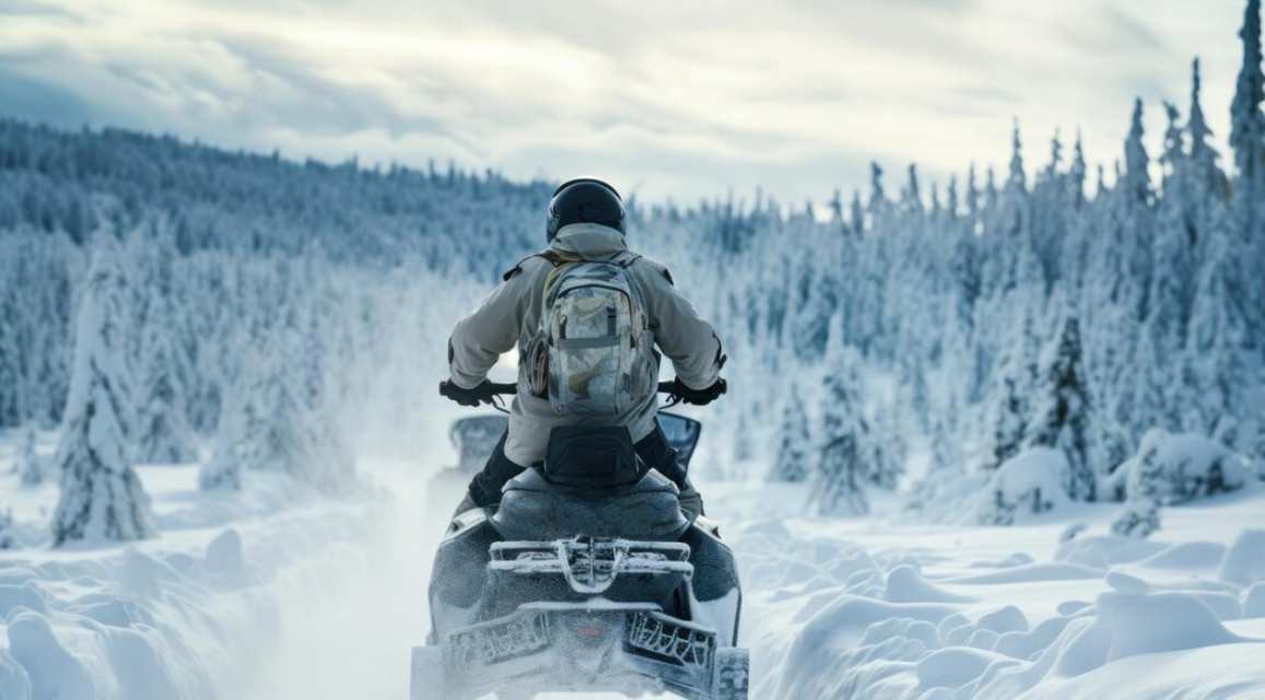 man on a snowmobile through the winter forest covered with snow