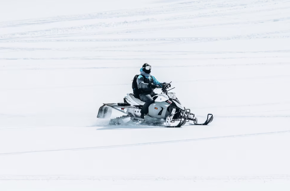 man riding a snowmobile in a large snowy field