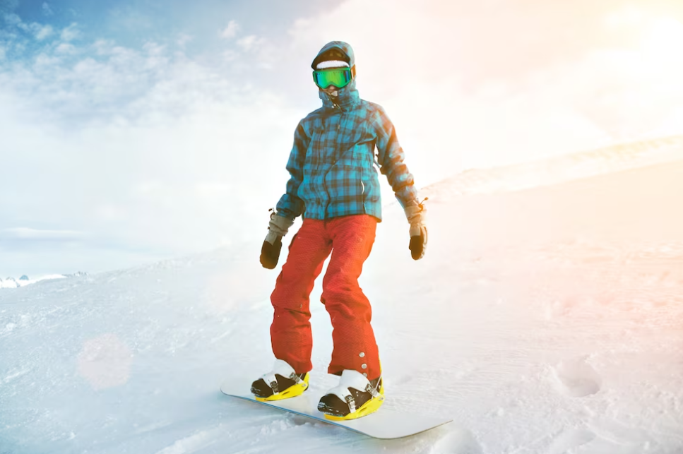 a person dressed in red pants and a blue jacket on snowboard