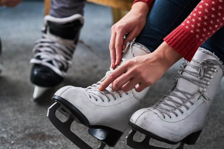 A close-up view of figure skate shoes being worn by a female