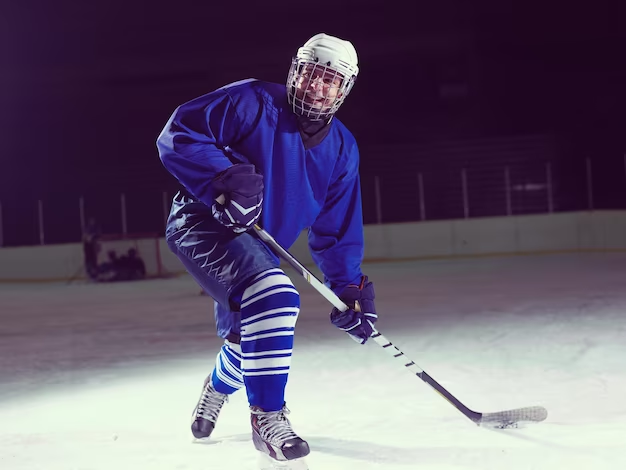 Man in complete hockey gear with stick on hockey field