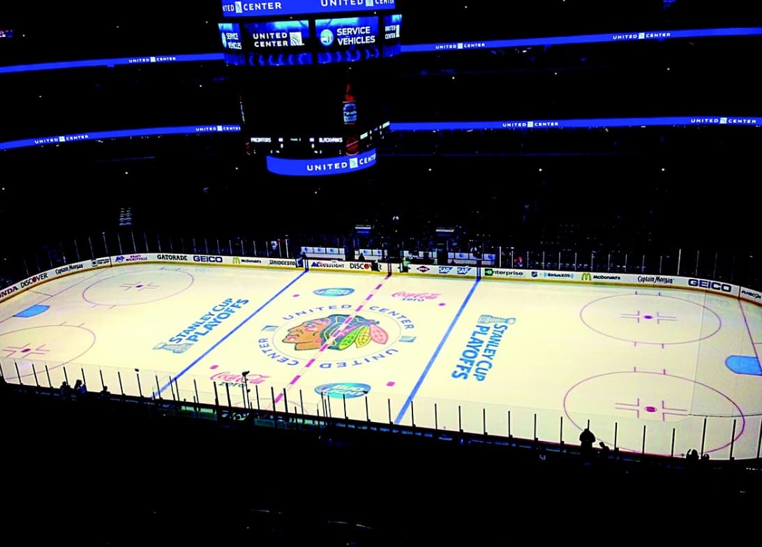 An elevated view of an ice hockey rink with team logos and an empty stadium