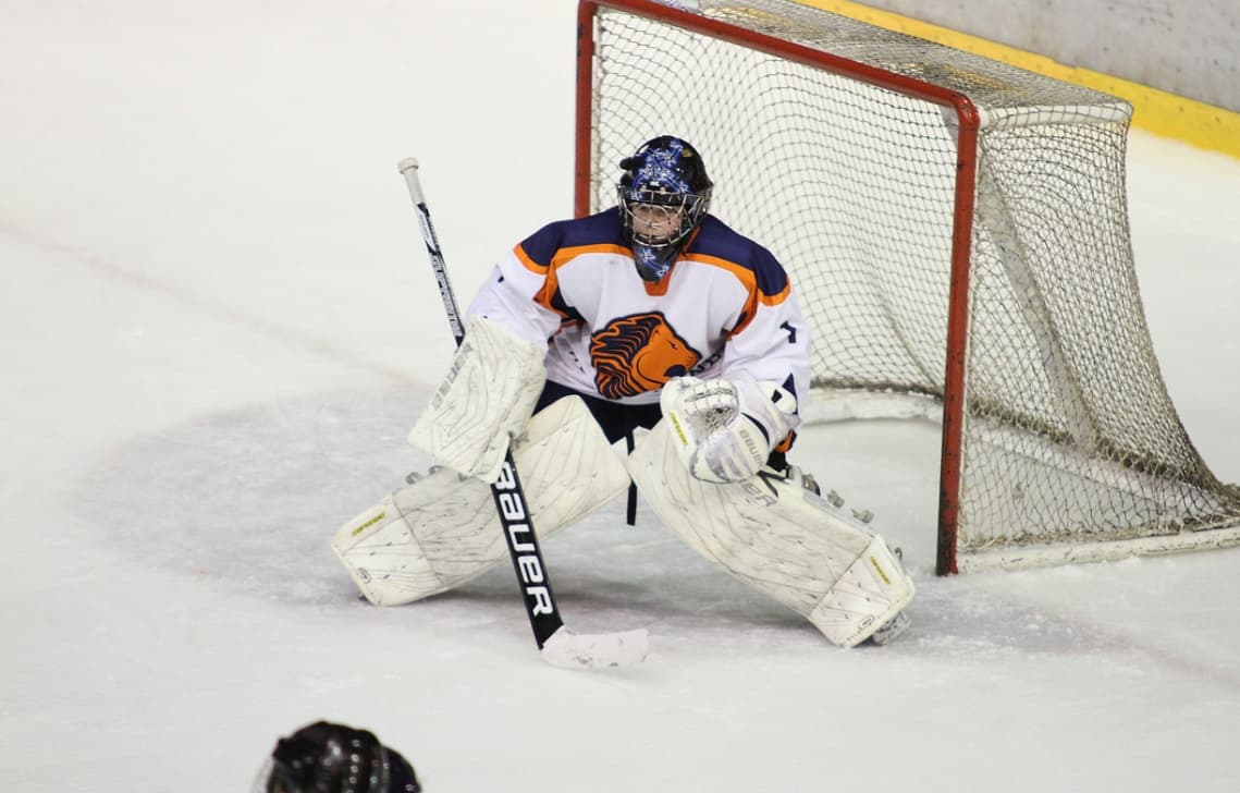 A hockey goalie crouched in front of the net during a game