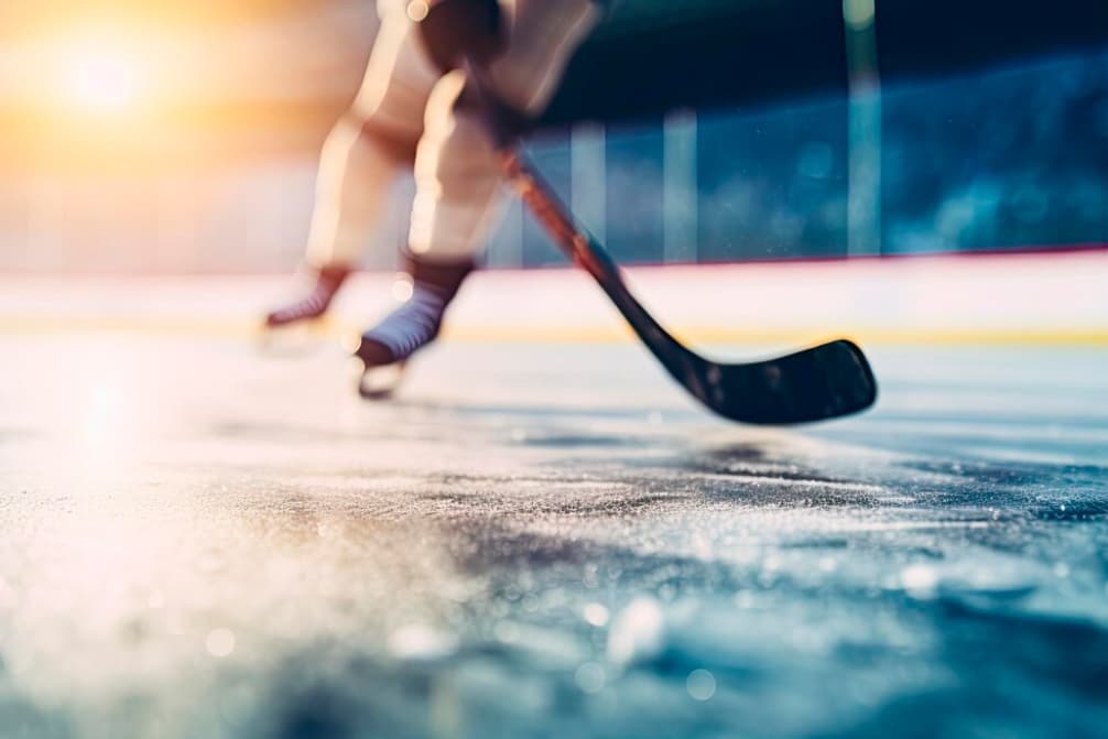 Close-up of a player's skates gliding on ice, stick and puck in motion