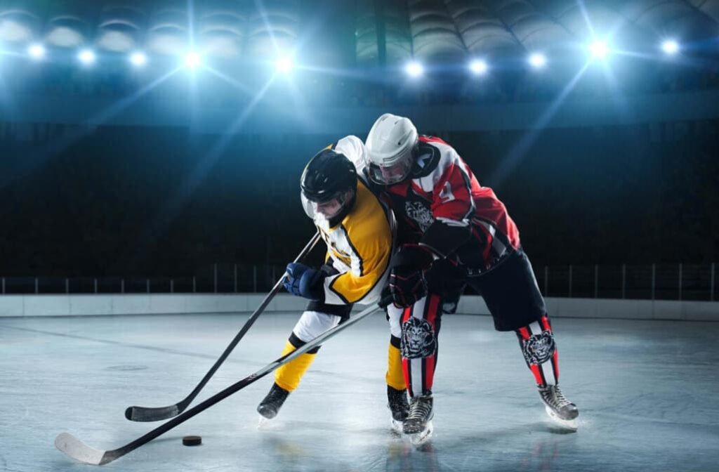 Two hockey players in a tense battle for puck control under bright lights