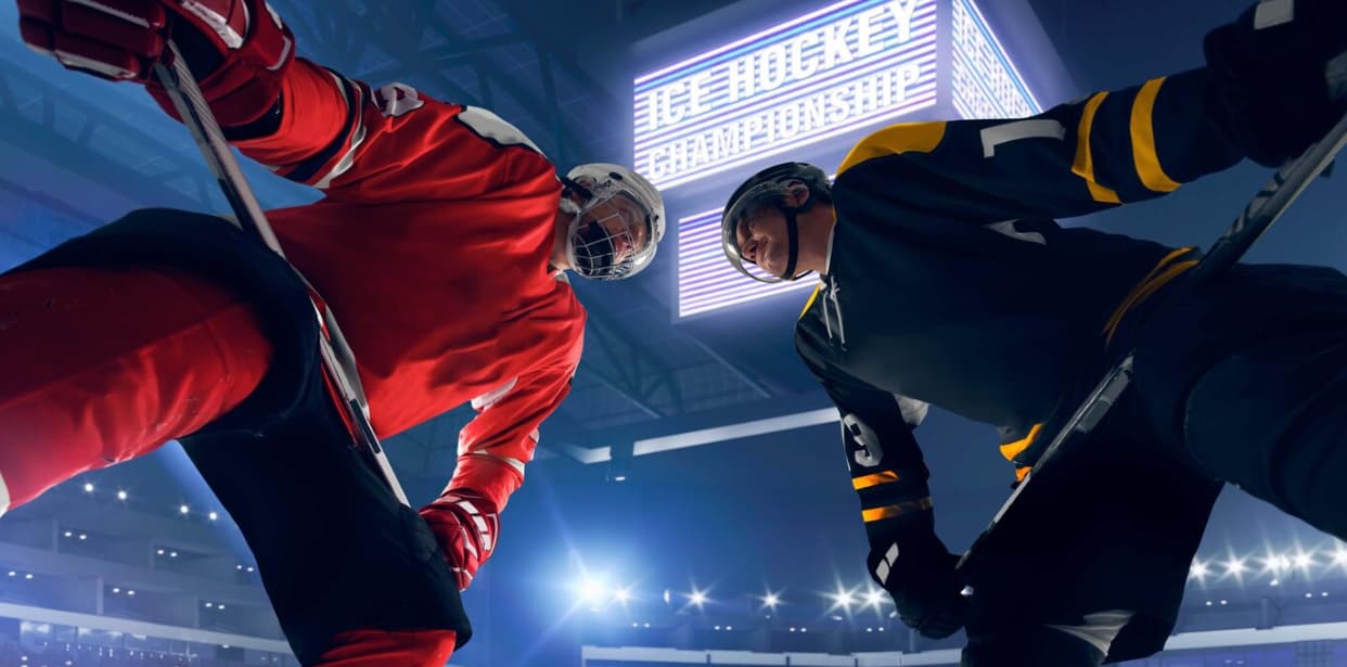 Two hockey players in red and navy face off under bright stadium lights