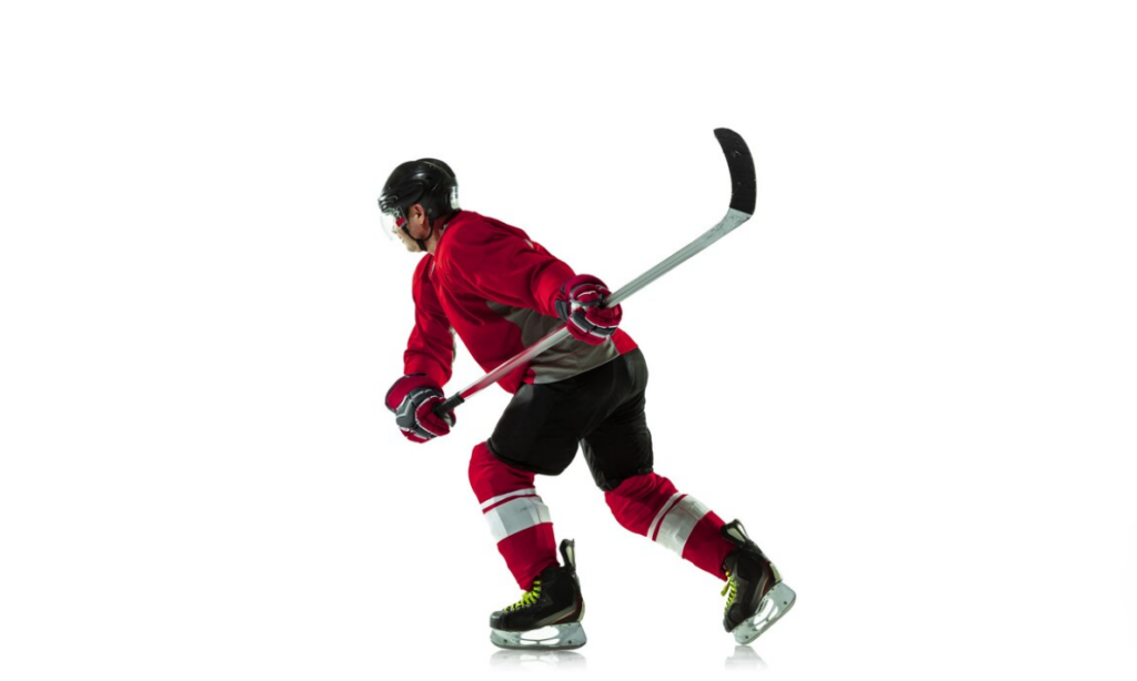 A hockey player in red skates aggressively with a puck