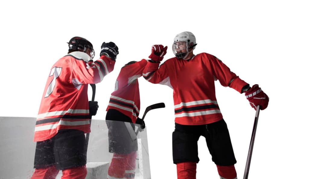 Two hockey players in red jerseys celebrate a victory on the ice